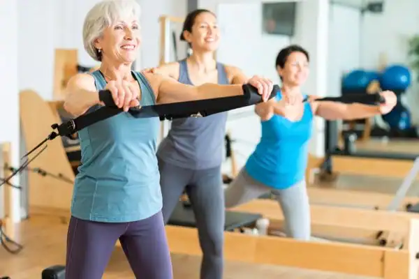 Toning Arms After 60: Empowering Womens Fitness Through Effective Weight Training 2 older woman doing weight training Nazeing and resistance in the gym to tone upper arms