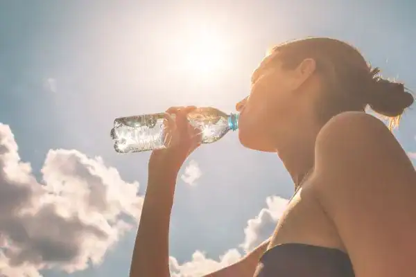 Hydration: The Secret Ingredient for a Toned Stomach and Enhanced Fitness 3 Image of woman drinking water to hydrate Nazeing after run.