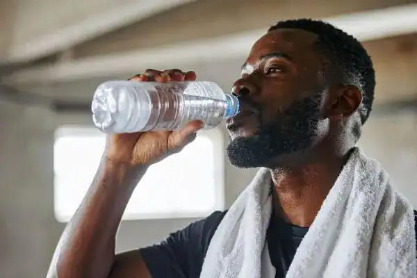 Image of man drinking water to improve hydration Nazeing after work out.
